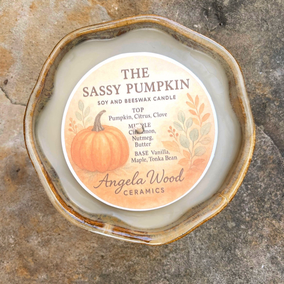 Ceramic candle with 'Sassy Pumpkin' label on a stone surface